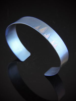 Minimalist titanium cuff bracelet with a matte finish and subtle etched geometric pattern. Slim 1/2" wide open cuff, small fit, modern and understated design.