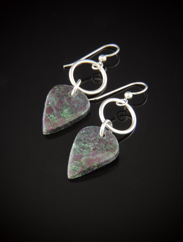 Pair of teardrop-shaped Ruby Fuchsite earrings with dark green and pink mottled patterns, hanging from sterling silver circular rings and earwires against a reflective black background.