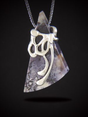 A geometric, triangular Purple Tiffany Stone pendant featuring intricate violet and white marbling, enveloped in an organic, molten-style sterling silver design. The pendant hangs from a dark gunmetal chain against a solid black background.