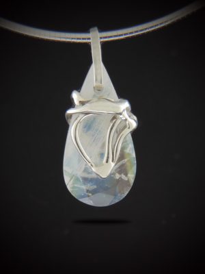 A teardrop-shaped rainbow moonstone pendant with a unique, hand-cast sterling silver swirl design hanging from a silver omega chain against a black background.