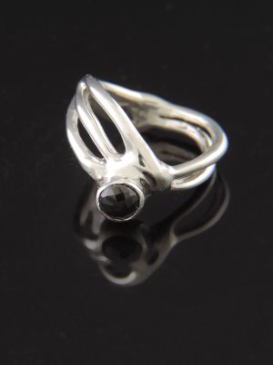 An organic sterling silver ring named Espresso Martini featuring a 5mm faceted rose-cut black spinel cabochon gemstone, shown on a reflective black surface.