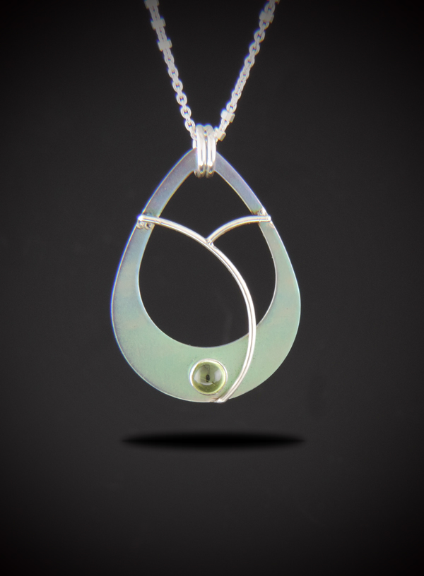 Alt Text: A teardrop-shaped titanium pendant necklace with an open center, showing a soft gradient color from lavender at the top to mint green at the bottom. A small, round green peridot gemstone is set at the bottom base, framed by elegant, curved sterling silver wire accents. The pendant hangs from a sterling silver chain against a dark gradient background.