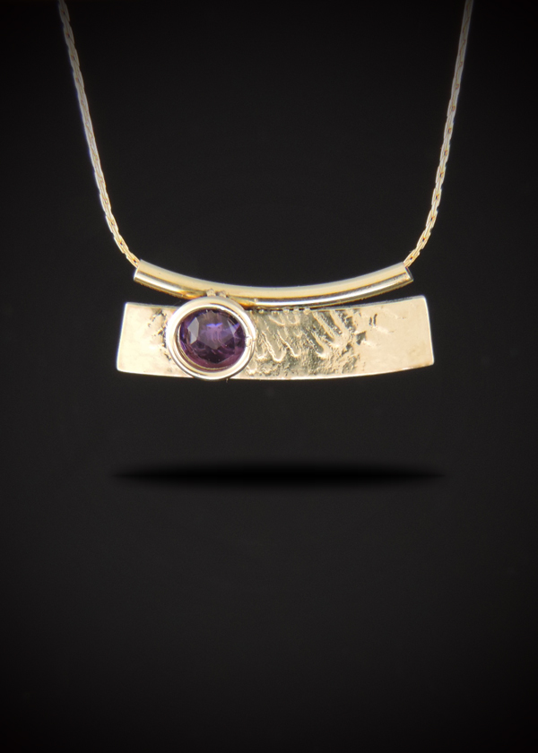 Handcrafted gold-filled bar pendant necklace featuring an organic roll-printed texture and a bezel-set 6mm rose-cut purple amethyst. The curved pendant hangs seamlessly from a sleek gold-filled Cardano chain passing through a matching tube bail, displayed against a dark gradient background.